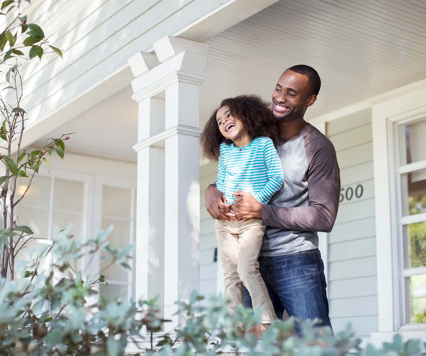 Father and daughter stand outside of their new home.