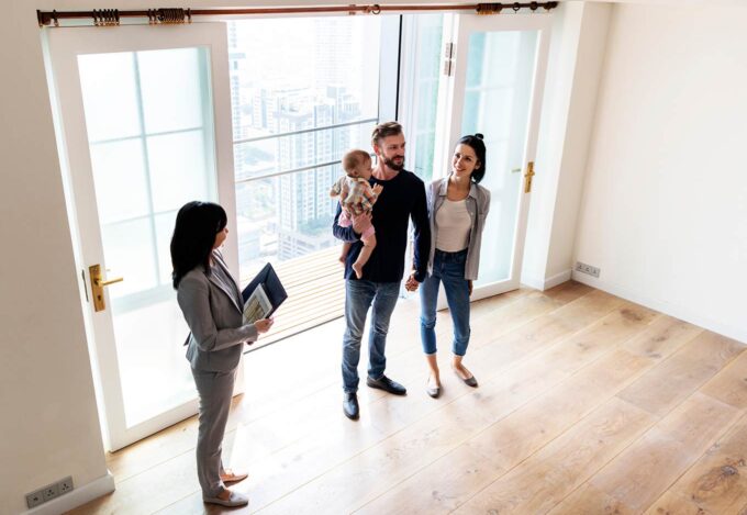 Couple and child tour home for sale during open house with real estate agent.