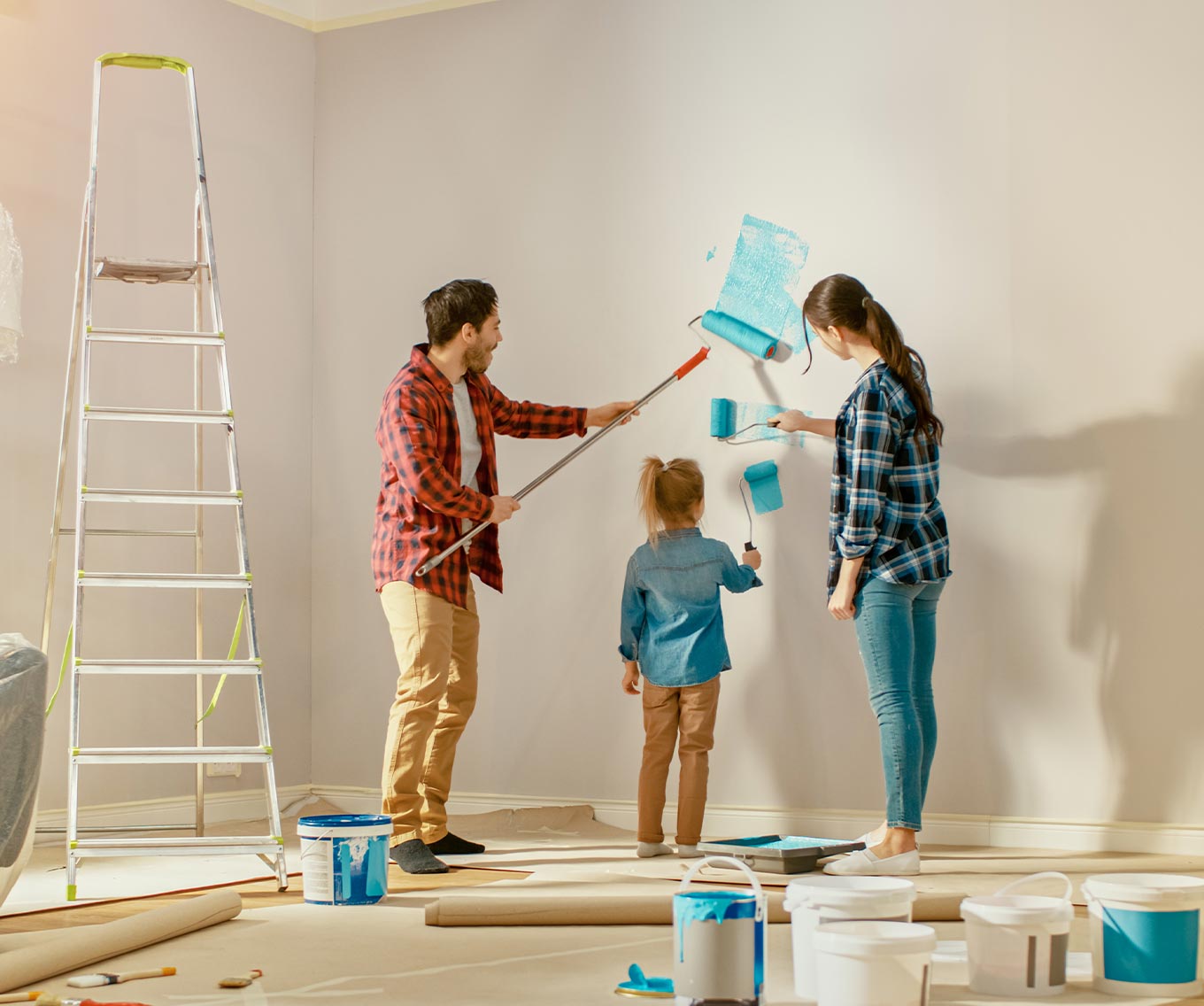 Family painting a wall and doing renovations on their fixer-upper.
